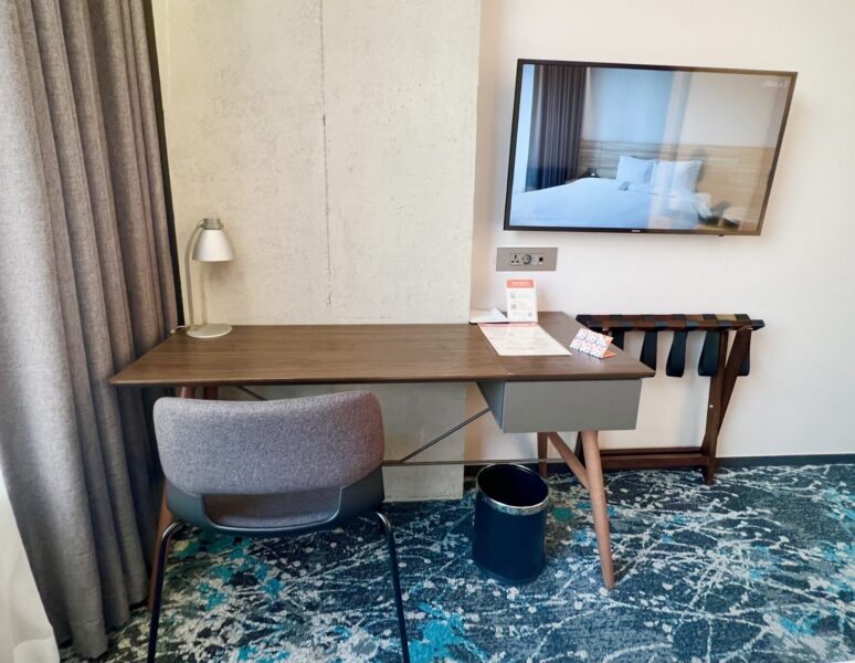 ホテルイン9江南のデスクとテレビ、スーツケースラック。
