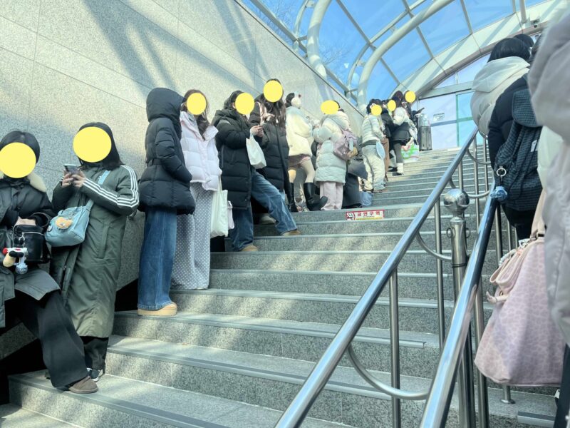 空港貨物ターミナル駅でインスパイアアリーナの臨時バスを待つ人々